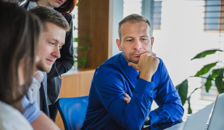 Man With Coworkers Thinking Scaled E1766063682250